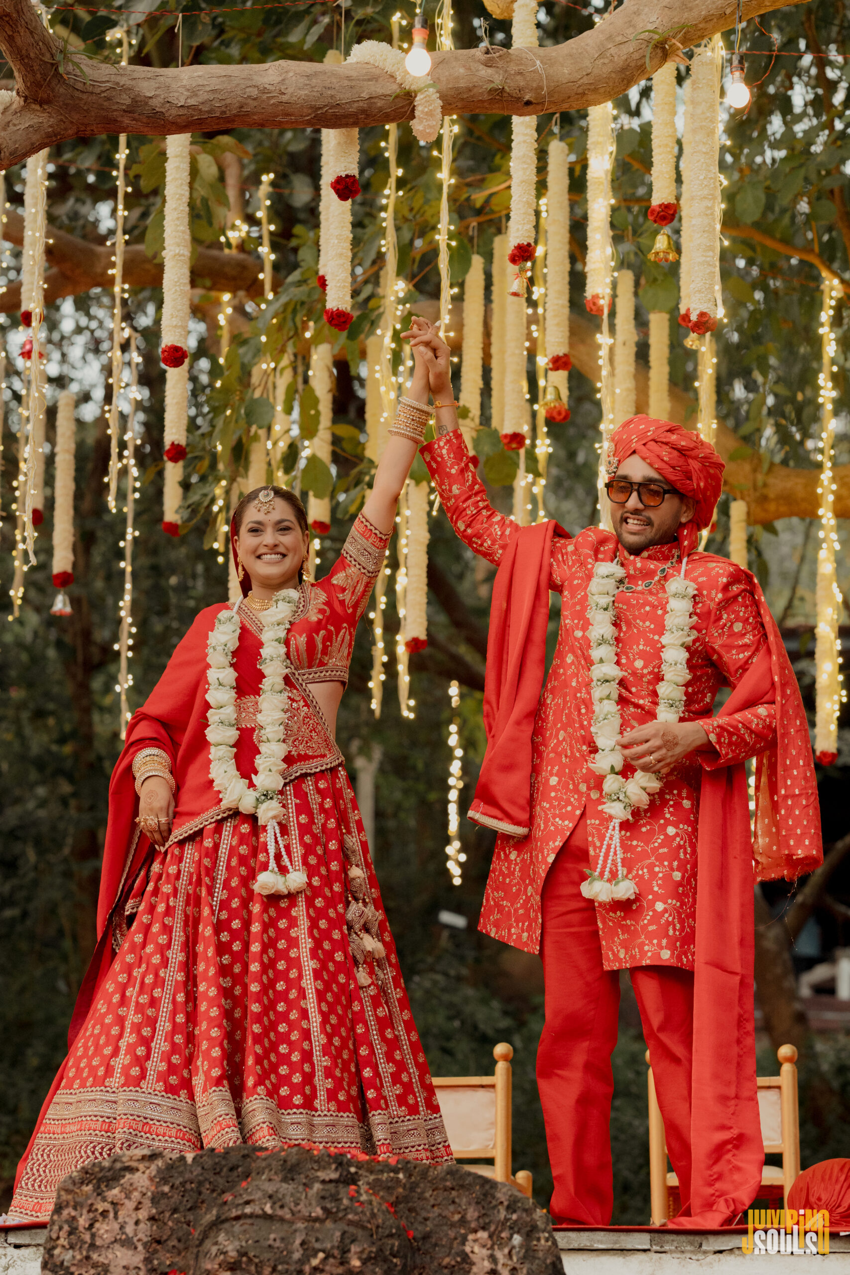 Kunal Iyengar music composer and Rachel D'Costa at their wedding in Goa in matching red outfits raising hands