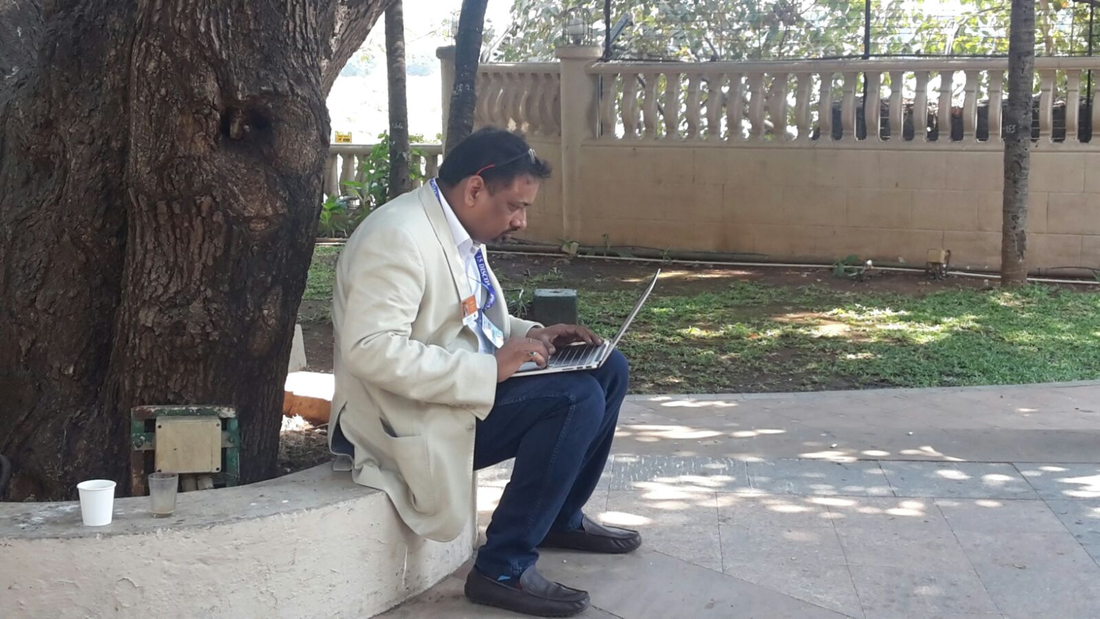 Sampath Iyengar working on laptop under a tree at Rotary district conference